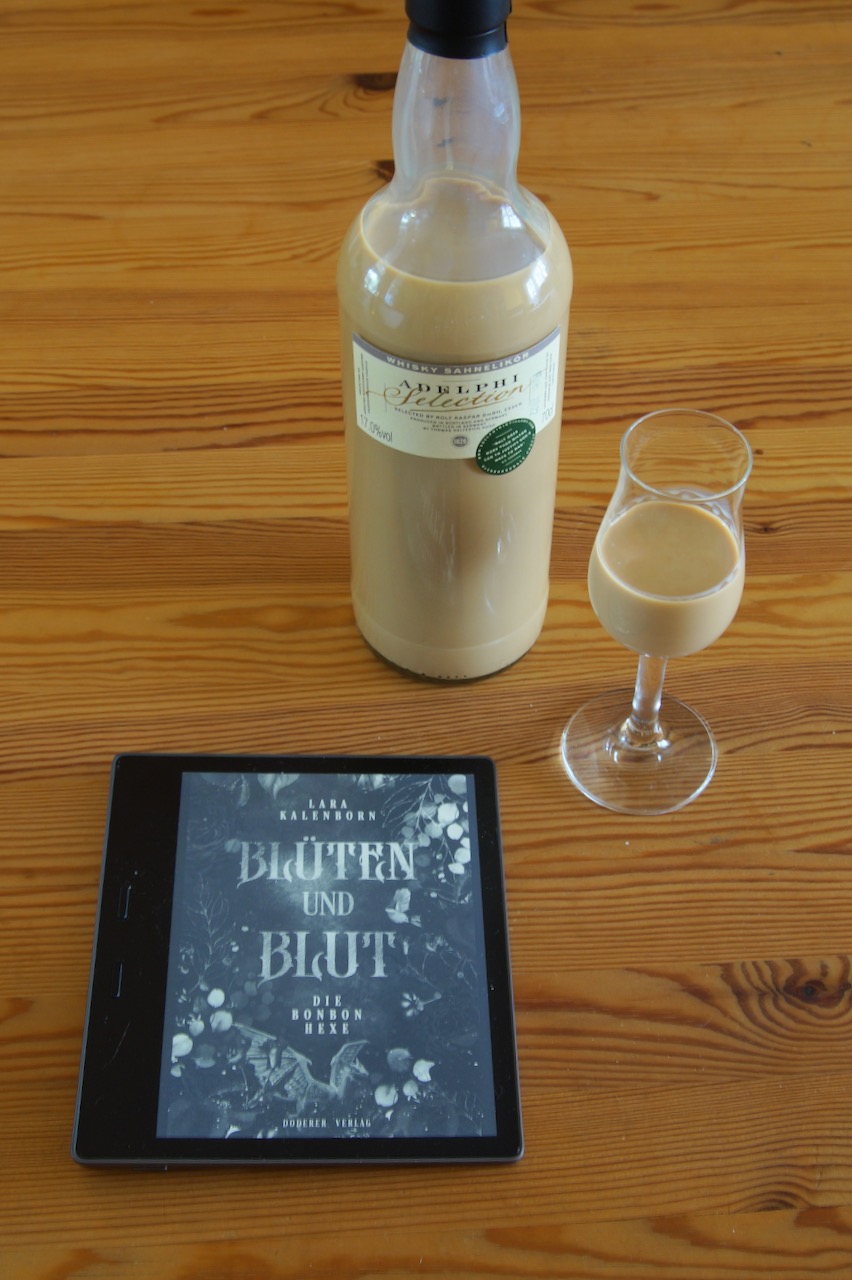 Cover von Blüten und Blut auf einem Kindle E-Book Reader mit 1 Glas Whisky-Sahne Likör von Adelphi und der passenden Flasche dazu.
